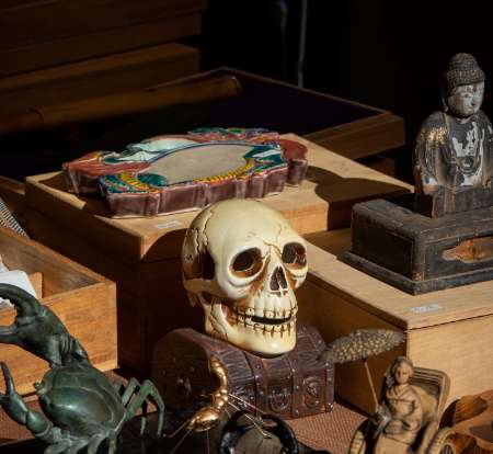 Foto von Kuriositäten auf einem Flohmarktstand, im Fokus ein Totenkopf