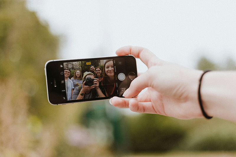 Foto eines Handys auf dem man sieht, wie menschen ein Selfie von sich machen